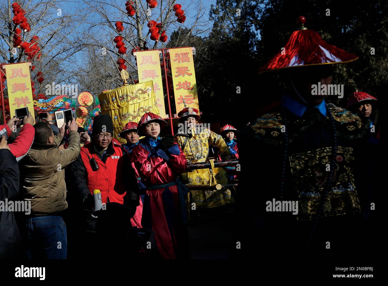 Qi Xue’en, a performer dressed as a Qing Dynasty emperor, seated on a sedan chair, center, is carried during the ancient Qing Dynasty ceremony in which emperors prayed for good harvest and fortune at a temple fair in Ditan Park during the first day of the Chinese Lunar New Year in Beijing, Monday, Feb. 8, 2016. Millions of Chinese began celebrating the Lunar New Year, which marks the Year of the Monkey on the Chinese zodiac. (AP Photo/Andy Wong) Stockfoto