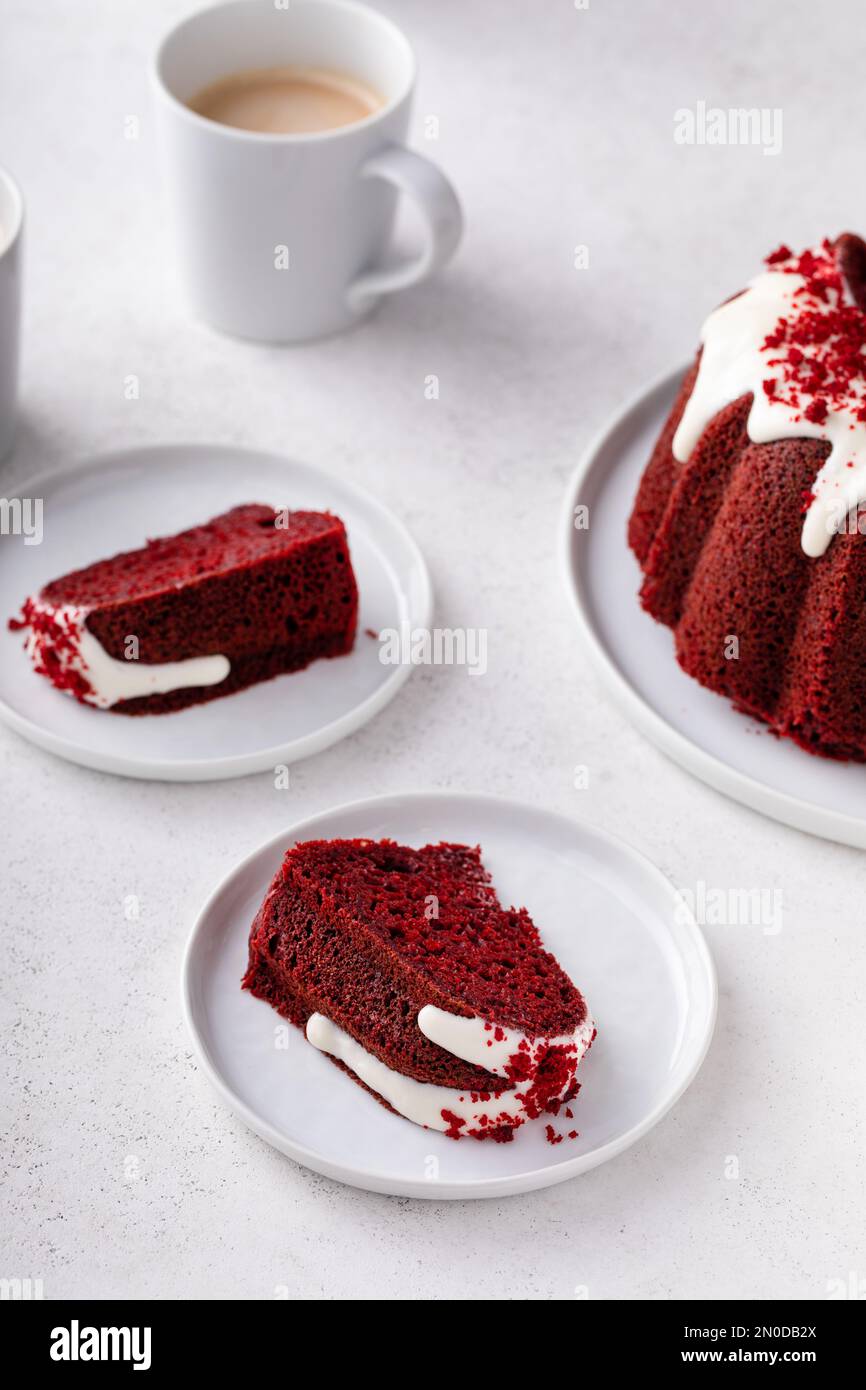 Roter Samtkuchen mit Frischkäse-Zuckerguss und Kuchenkrümeln auf den oberen Scheiben auf einem Teller Stockfoto