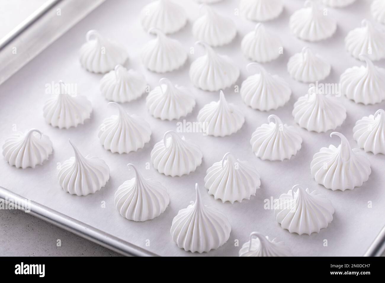 Baiser-Küsse auf einem Backblech, fertig zum Backen, selbstgemachte Kekse-Idee Stockfoto