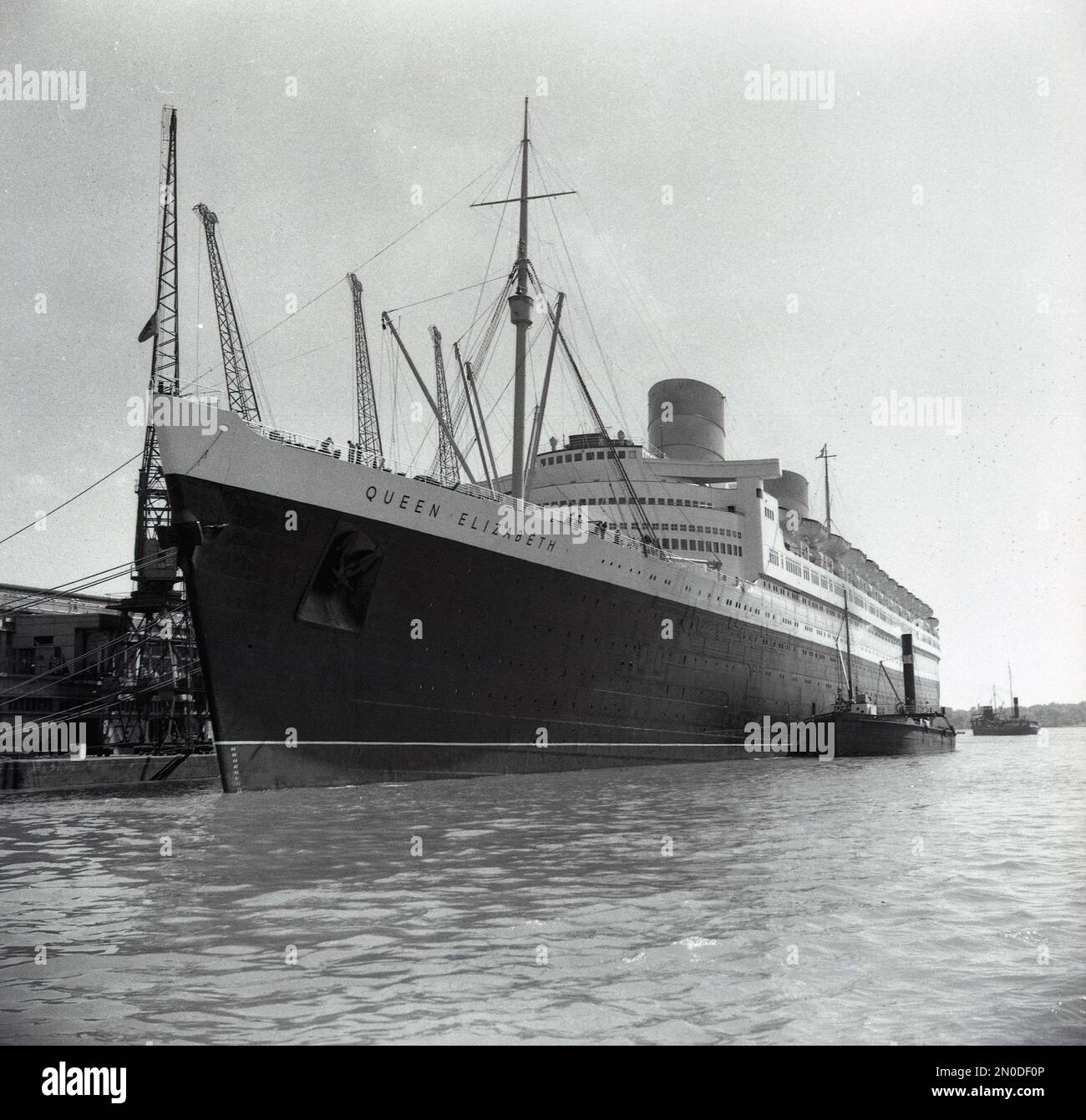 1950er, historisch, RMS Queen Elizabeth liegt an den Docks in Southampton, Hampshire, England, Großbritannien. Das luxuriöse Seeschiff wird von der Cunard Line betrieben und segelte wöchentlich von Southampton, England, nach New York, USA, über Cherbourg in Frankreich. Erbaut in den 1930er Jahren von John Brown & Co am Clyde in Schottland, wurde sie zu Ehren von Königin Elizabeth, später Königin Mutter, benannt. Als sie 1938 gestartet wurde, war sie das größte Passagierschiff, das je gebaut wurde, bis 1994. Stockfoto