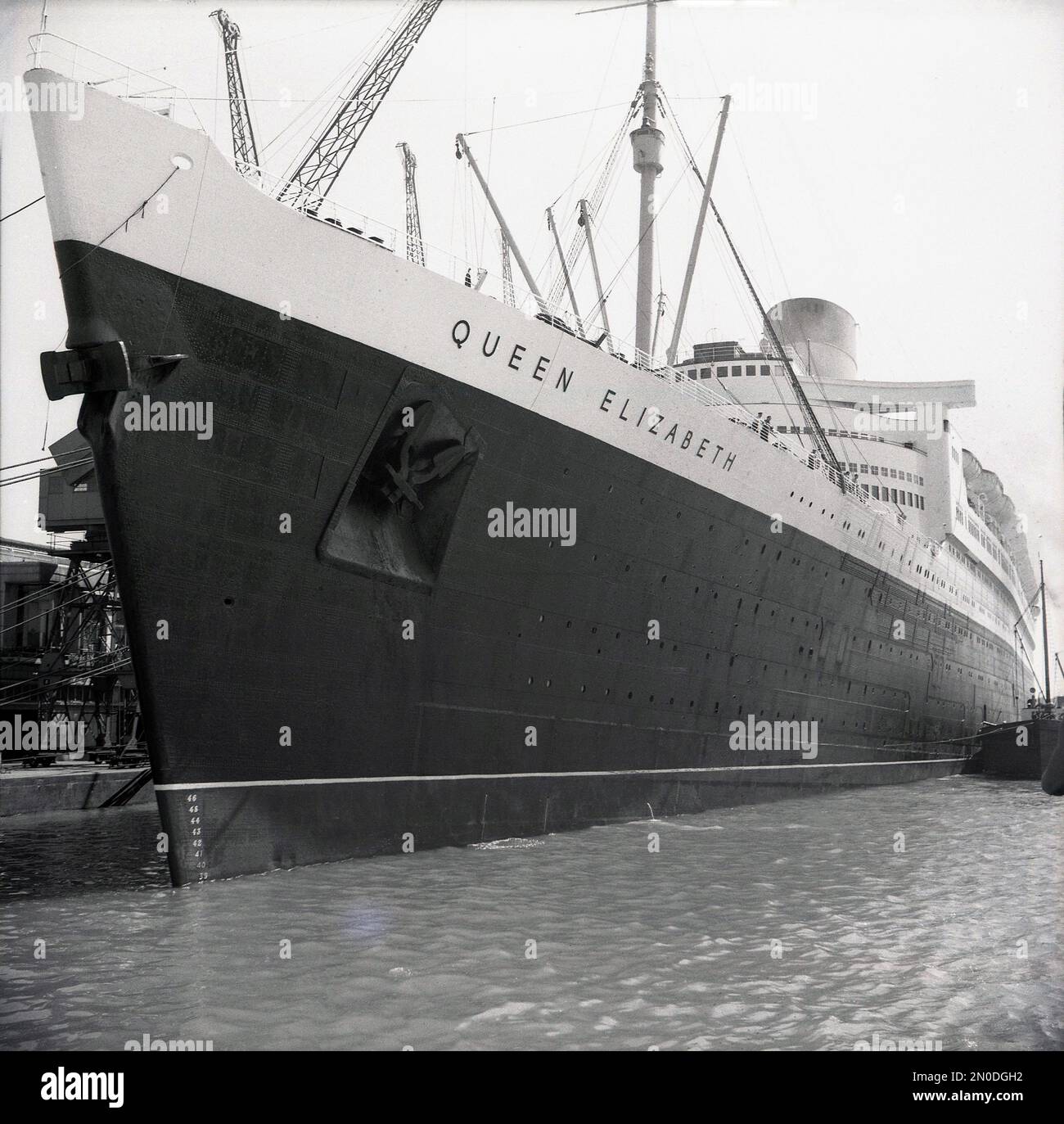 1950er, historisch, RMS Queen Elizabeth liegt an den Docks in Southampton, Hampshire, England, Großbritannien. Das luxuriöse Seeschiff wird von der Cunard Line betrieben und segelte wöchentlich von Southampton, England, nach New York, USA, über Cherbourg in Frankreich. Erbaut in den 1930er Jahren von John Brown & Co am Clyde in Schottland, wurde sie zu Ehren von Königin Elizabeth, später Königin Mutter, benannt. Als sie 1938 gestartet wurde, war sie das größte Passagierschiff, das je gebaut wurde, bis 1994. Stockfoto