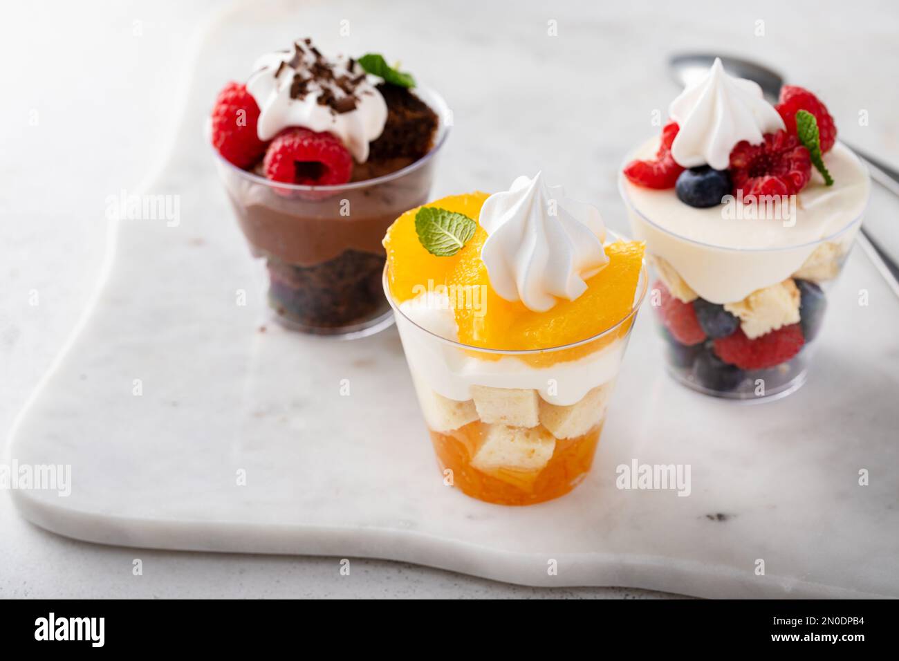 Auswahl an kleinen Desserts in Tassen, Schokolade, Beeren und Orangen Kleinigkeiten oder Parfaits Stockfoto