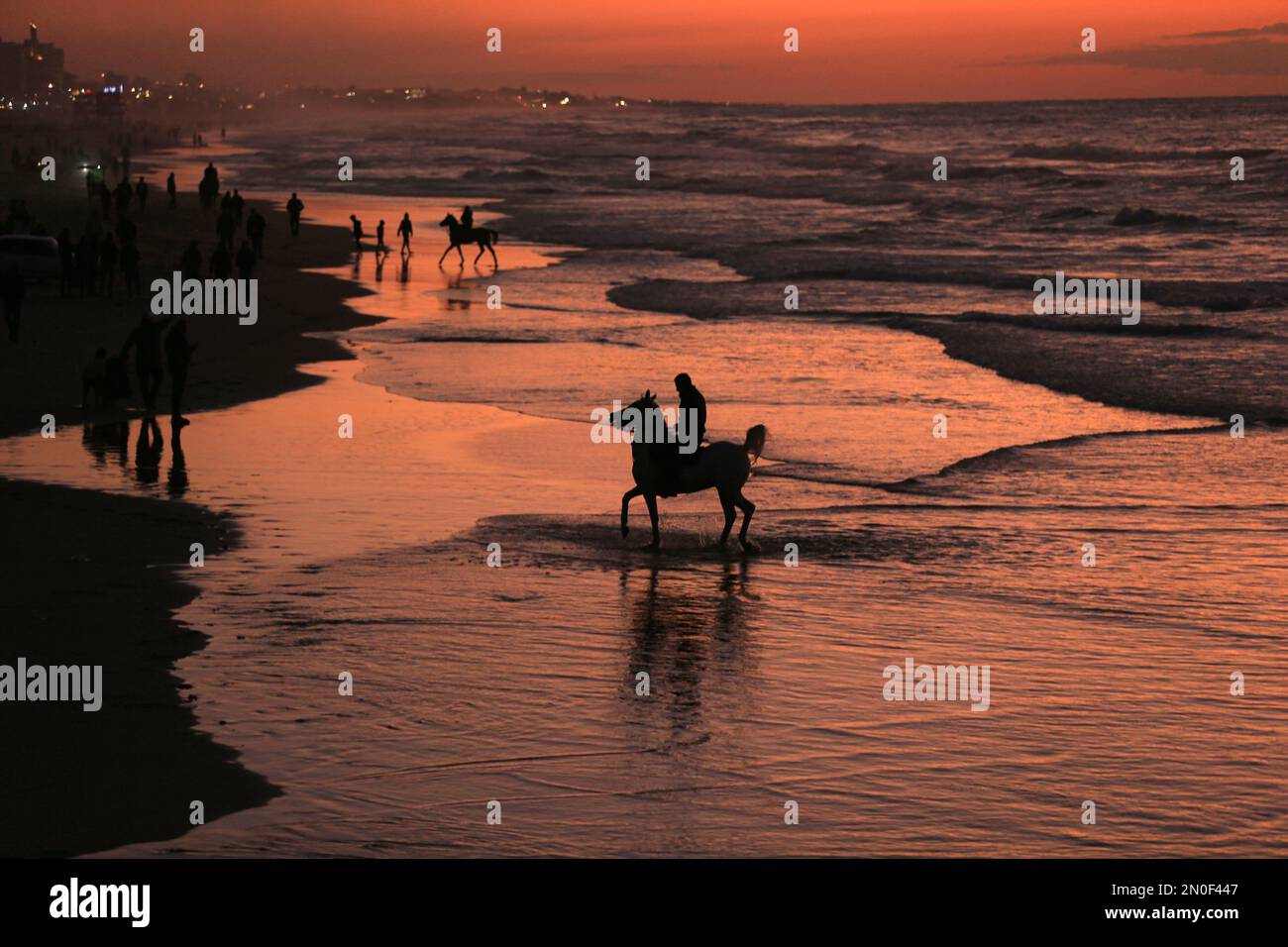 Ein Palästinenser reitet während des Sonnenuntergangs am Strand von Gaza City auf seinem Pferd. Gaza-Stadt. Palästina. Stockfoto