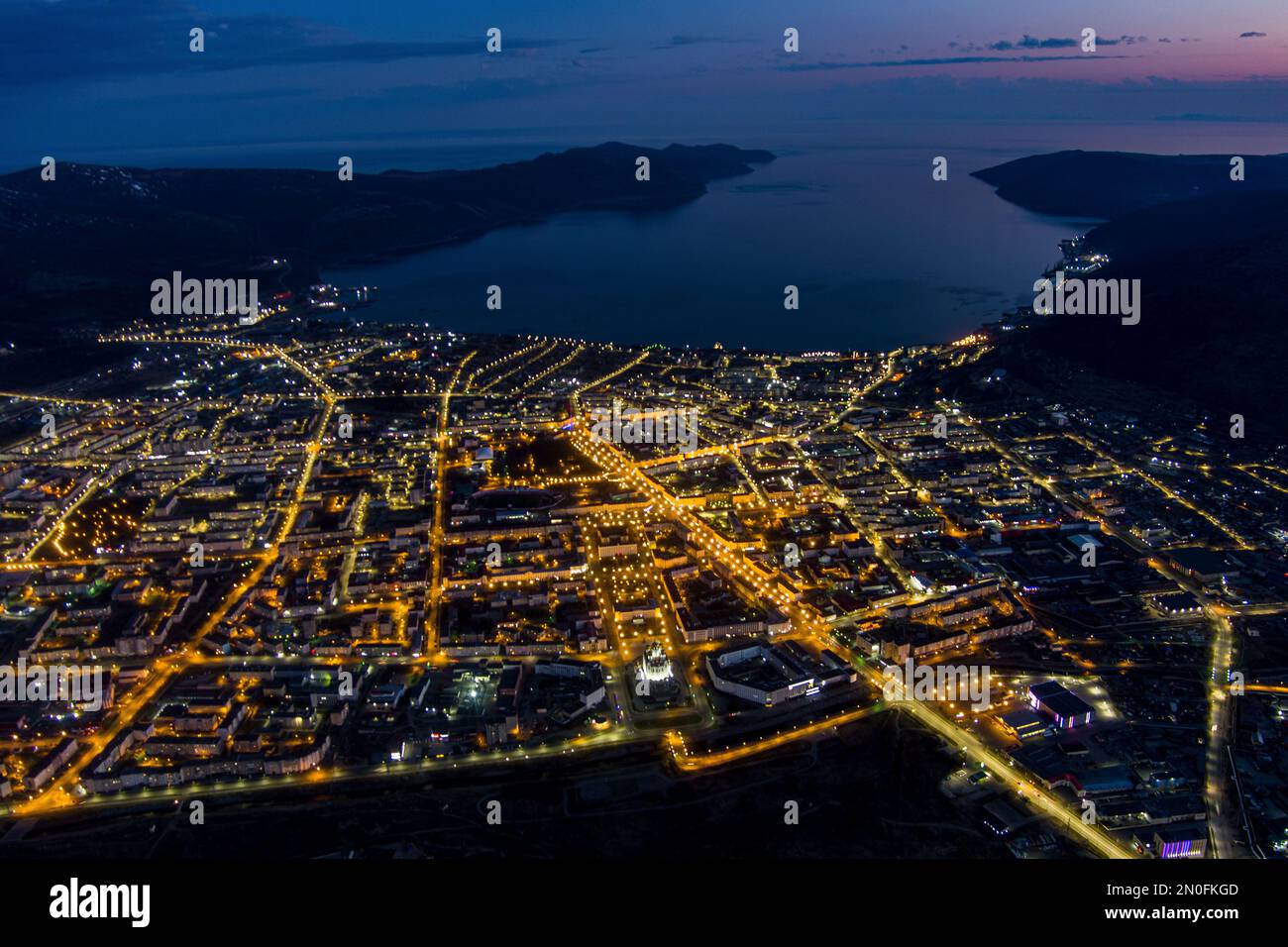 Nachtsicht auf Magadan aus der Höhe. Große Stadt im Fernen Osten Russlands. Das Verwaltungszentrum der Magadan-Region. Viele Gebäude und wunderschön Stockfoto