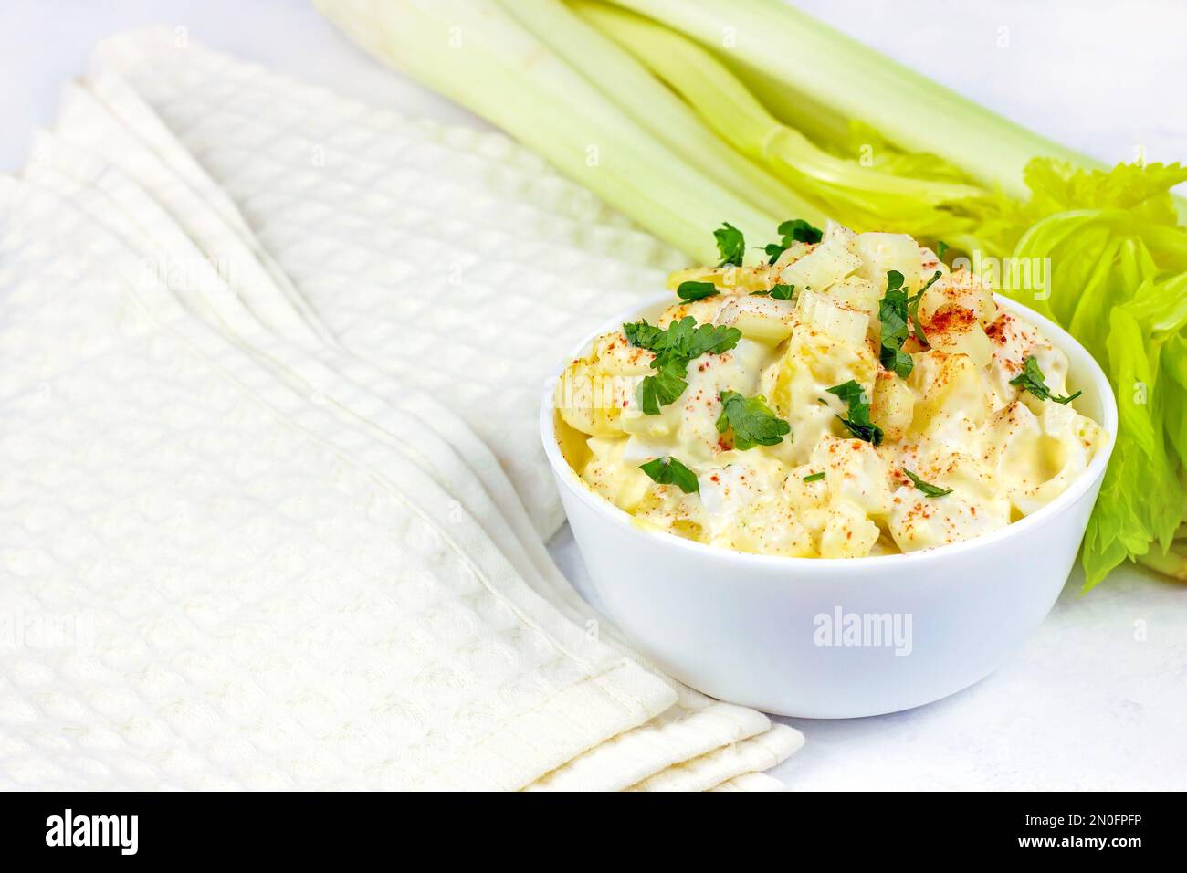 Frischer, hausgemachter traditioneller Amish-Kartoffelsalat mit Kartoffeln, gekochten Eiern, cremigem Dressing und Sellerie in einer weißen Schüssel, fertig zum Abendessen. Stockfoto