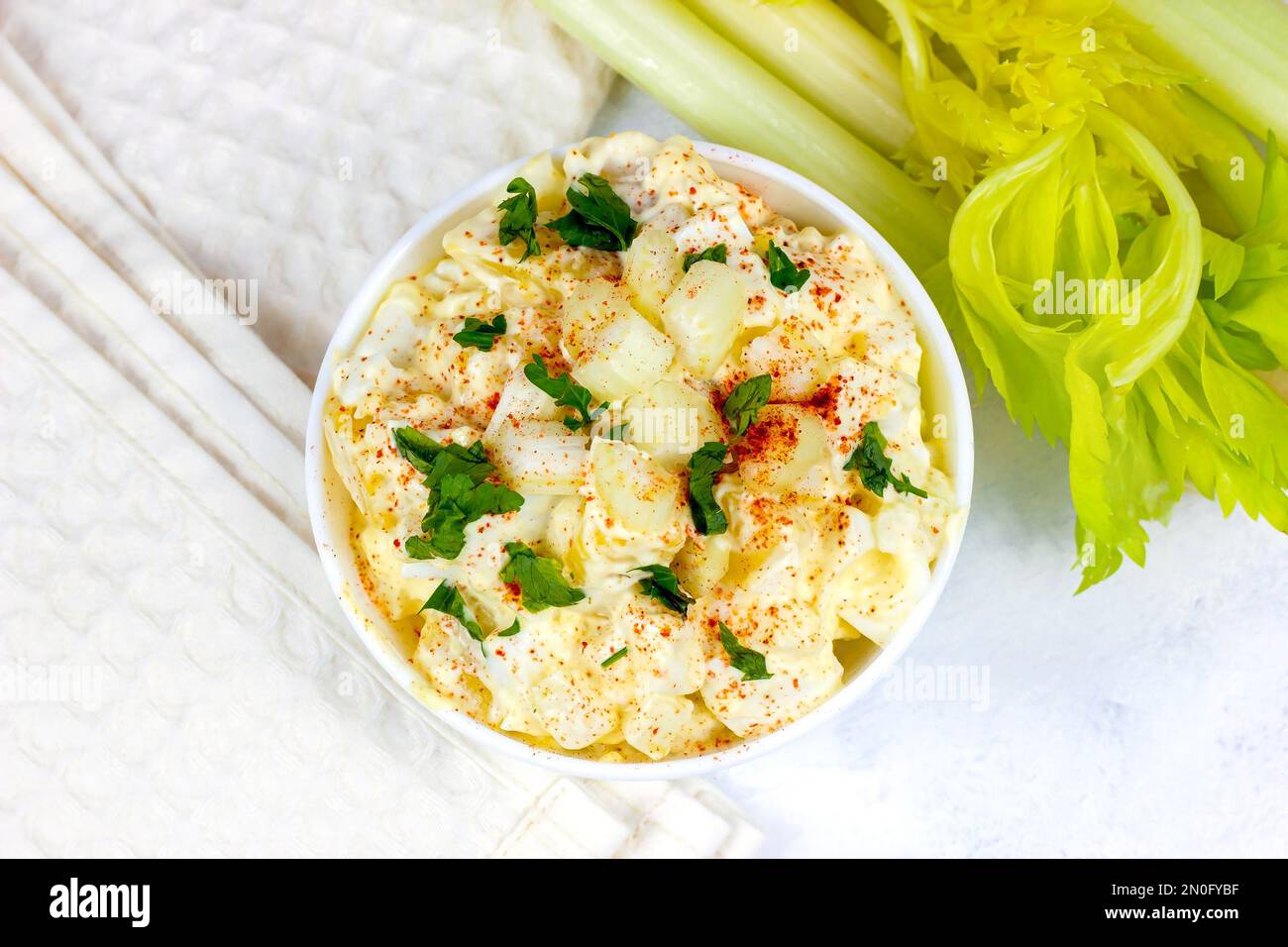 Frischer, hausgemachter traditioneller Amish-Kartoffelsalat mit Kartoffeln, gekochten Eiern, cremigem Dressing und Sellerie in einer weißen Schüssel auf hellem Hintergrund Stockfoto