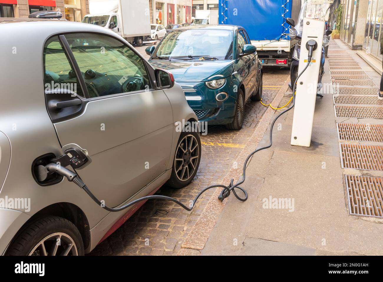 Aufladen eines kleinen grauen und grünen Elektroautos auf einer Straße der Stadt Stockfoto