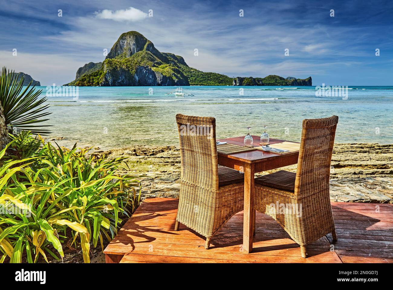Außenterrasse des Strandrestaurants am Meer mit Tisch und Stühlen, wunderschöner Blick auf die Insel Cadlao, El Nido, Philippinen Stockfoto