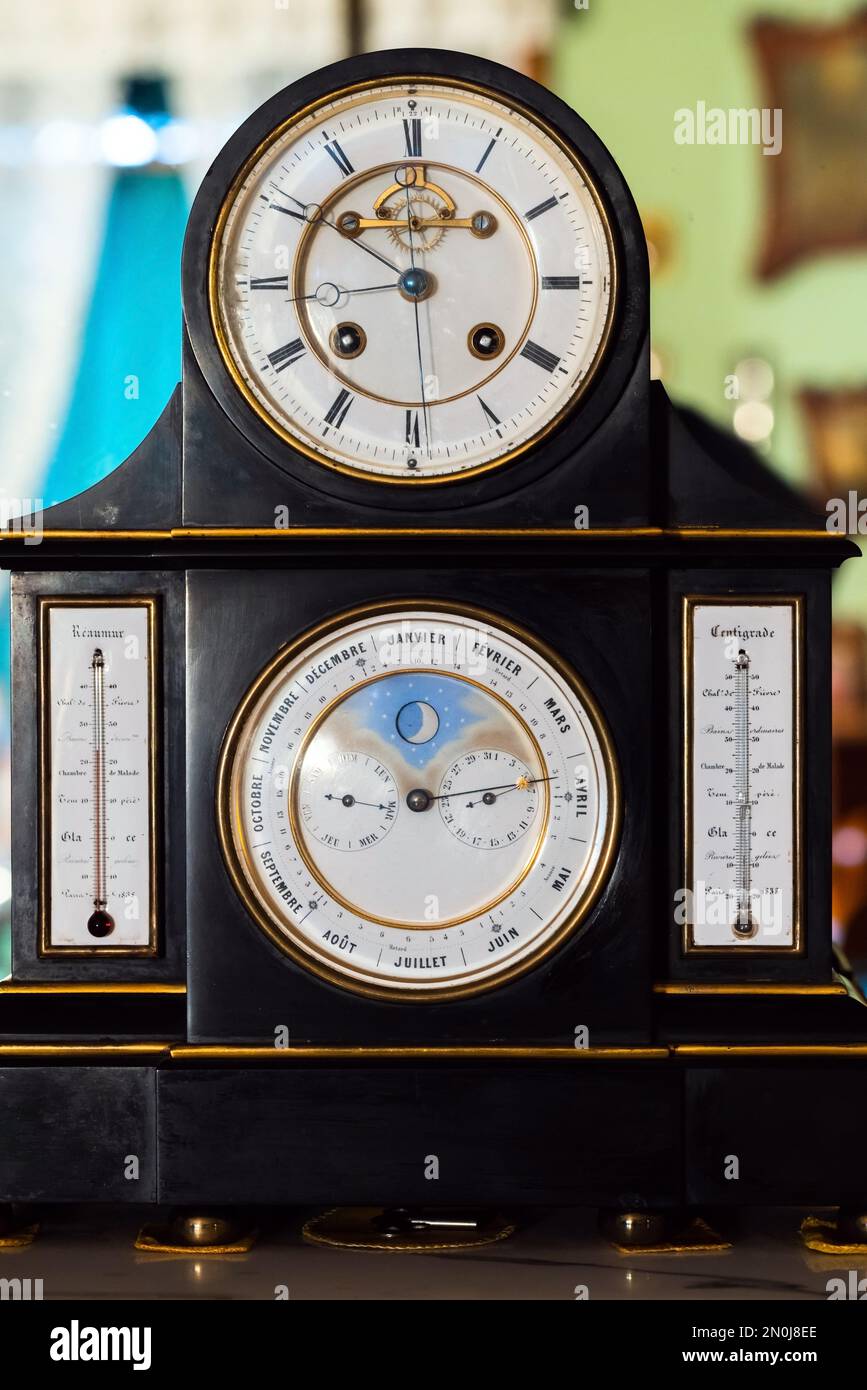 Klassische Tischuhr mit weißem Deal, retrogradem Kalender, Mondphasenanzeige, Reaumur- und Celsius-Temperaturskalen. Nahaufnahme des frontalen Fotos Stockfoto