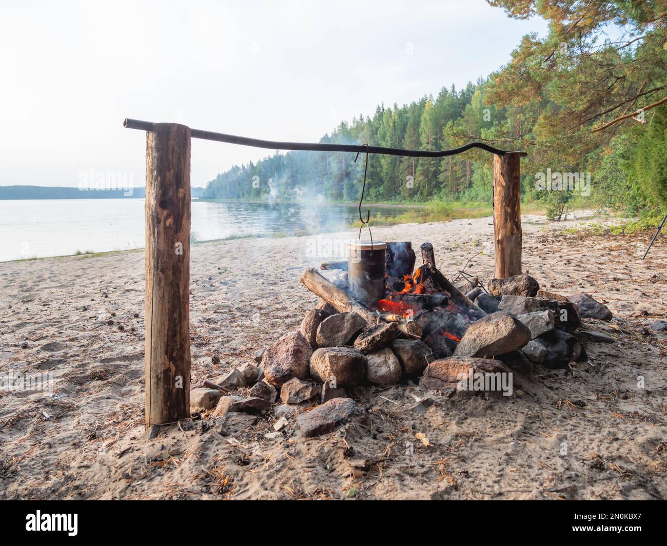 Kochen im Topf über Feuer. Touristisches Camp am Sandstrand des Sees Kenozero. Camping und Wandern in Karelien, Russland. Stockfoto