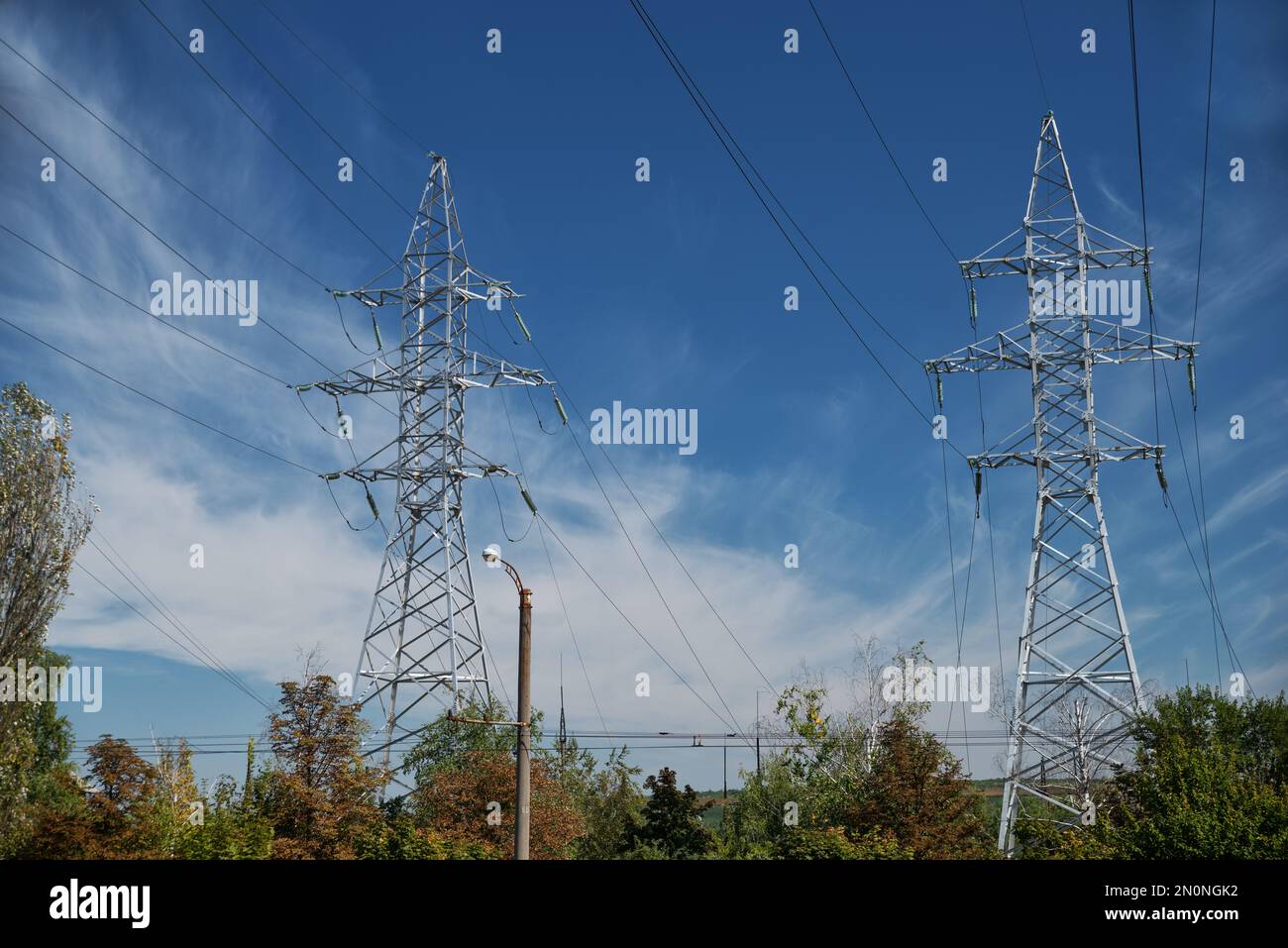 Turm mit Hochspannungsleitungen gegen den blauen Himmel. Hochspannungsturm. Elektrische Leitungen und Sicherungen. Energiegeschäft. Energie in Staub Stockfoto