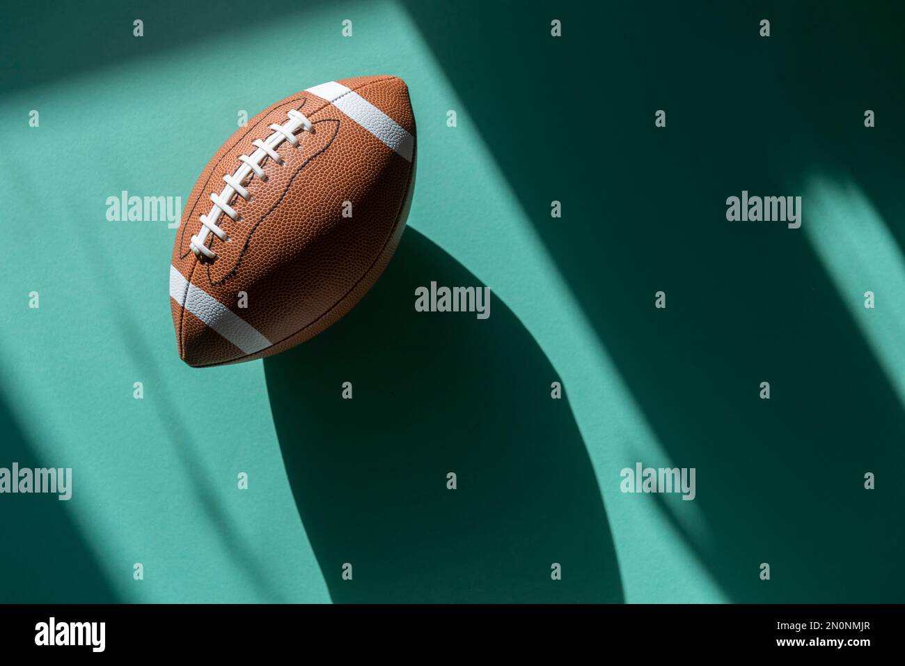 American Football-Lederball mit mintfarbenem Hintergrund. Draufsicht. Spielausrüstung horizontales Sportposter, Grußkarten, Kopfzeilen, Website und Stockfoto