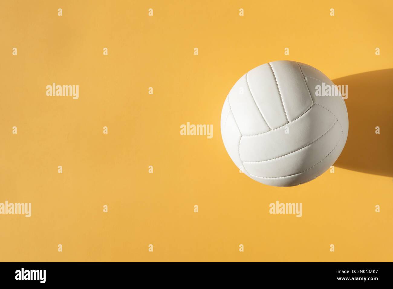 Weißer Volleyball-Lederball auf gelbem Hintergrund. Draufsicht. Spielausrüstung horizontales Sportposter, Grußkarten, Kopfzeilen, Website und App Stockfoto