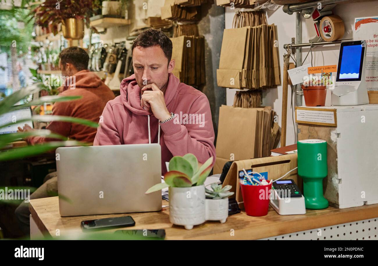 Mann mit Laptop auf der Ladentheke Stockfoto