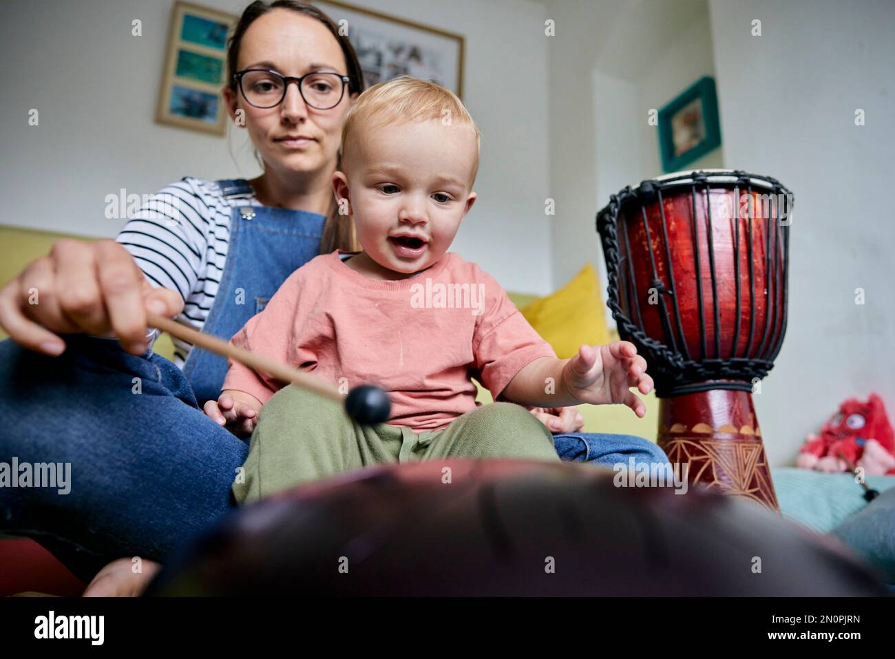 Mutter und Kleinkind spielen im Haus zusammen ein Musikinstrument Stockfoto