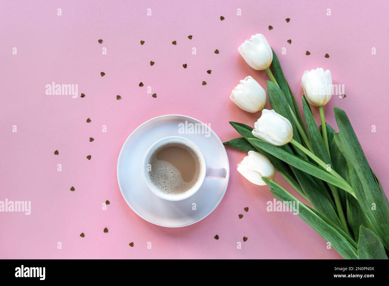 Kaffeetasse, weiße Tulpen und herzförmiges Konfetti auf pinkfarbenem Hintergrund. Valentinstag, Frühjahrsferien-Konzept. Draufsicht, flach liegend. Stockfoto