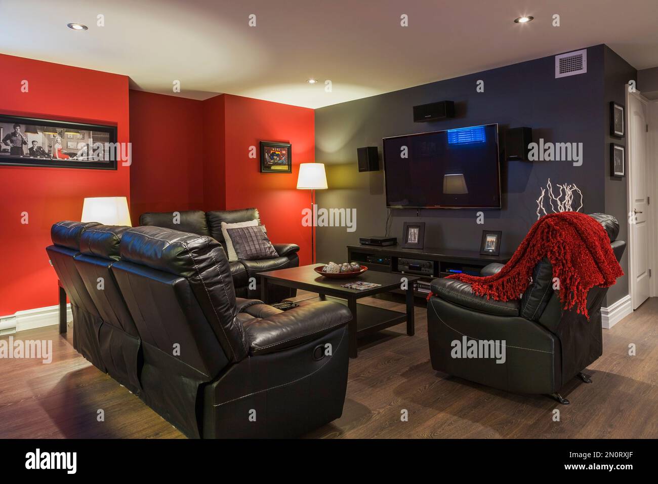 Schwarze Ledersofas und Lehnsessel mit hölzernem Couchtisch im Familienzimmer im Keller eines modernen Landhauses. Stockfoto