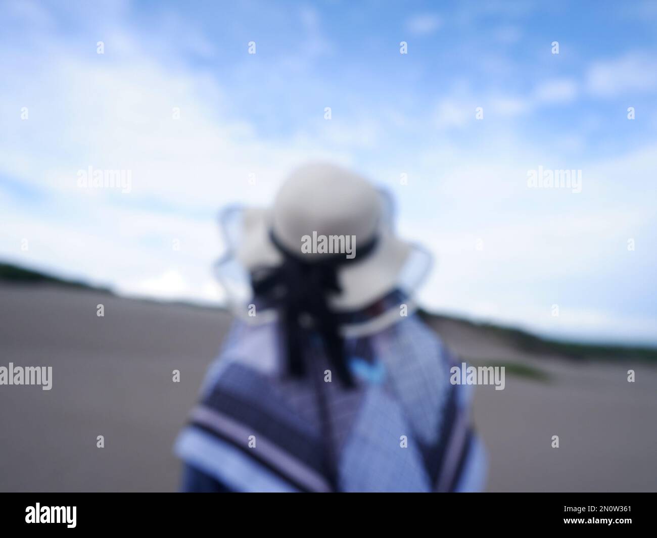 Blur Back Foto einer Frau mit Hut am tropischen Strand mit Blick auf Himmel und Meer Stockfoto