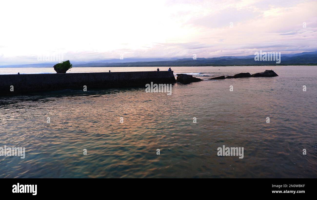 Nachmittagsblick auf das Meer und die Mauer, den Strand und die Korallen, Hintergrund bei Sonnenuntergang am Strand Santolo Indonesia Stockfoto