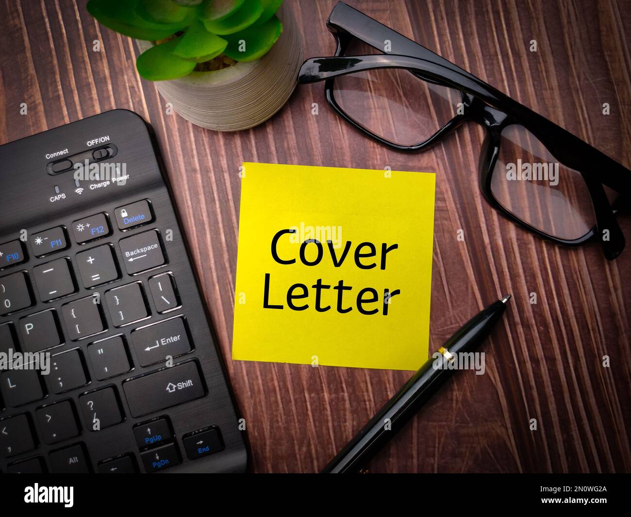 Tastatur, Stift und Brille mit dem Wort Anschreiben auf Holztisch. Stockfoto