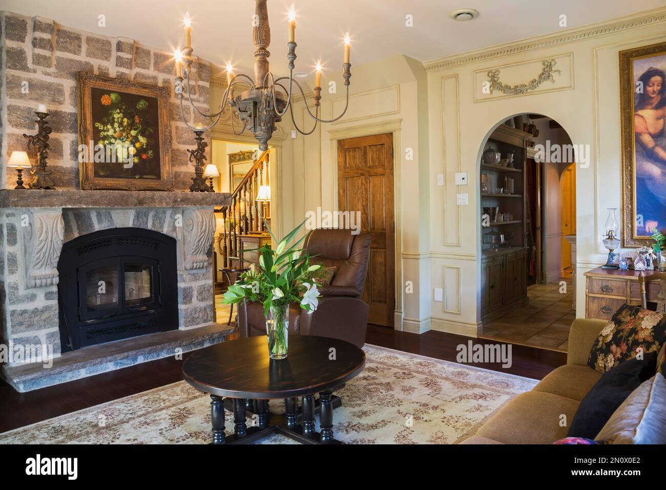 Grauer Natursteinkamin und runder hölzerner Couchtisch im Wohnzimmer im Haus im Renaissance-Stil. Stockfoto