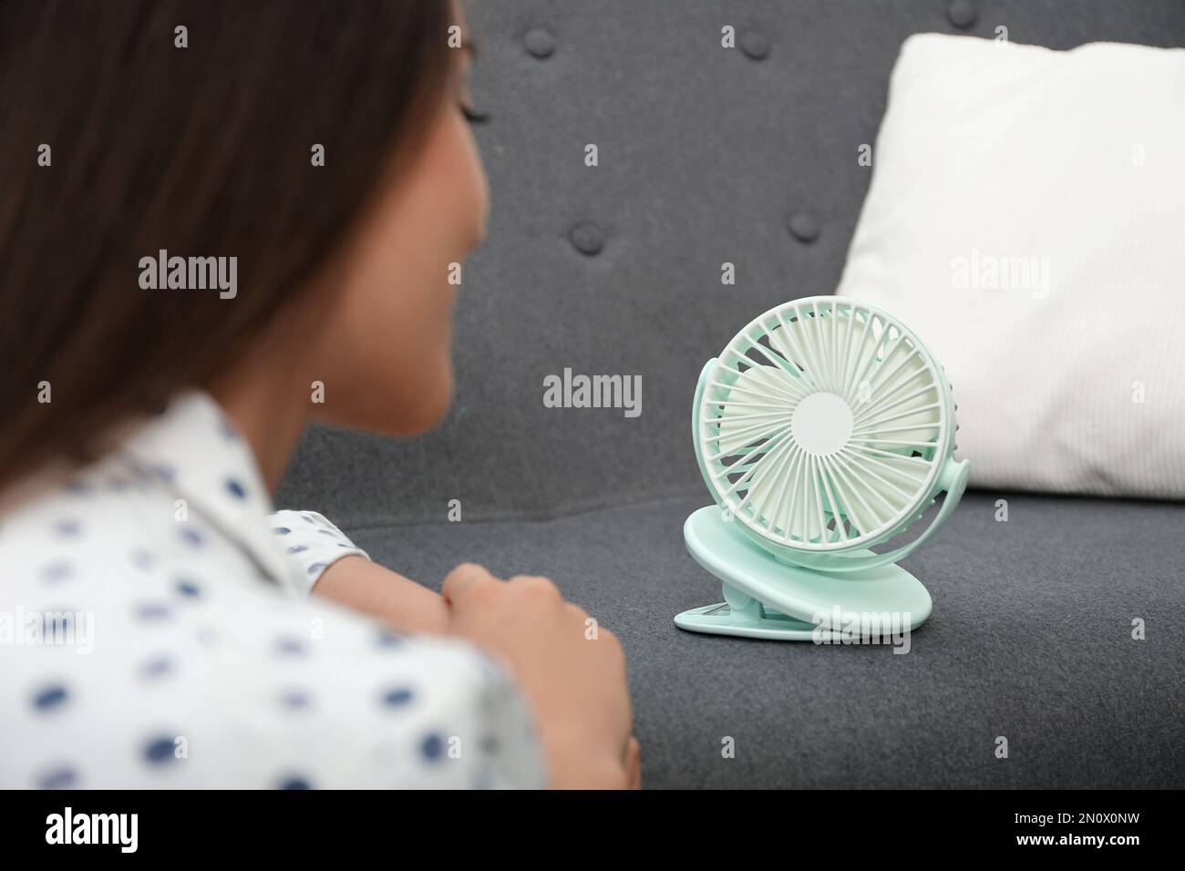 Frau mit tragbarem Ventilator zu Hause. Sommerhitze Stockfoto