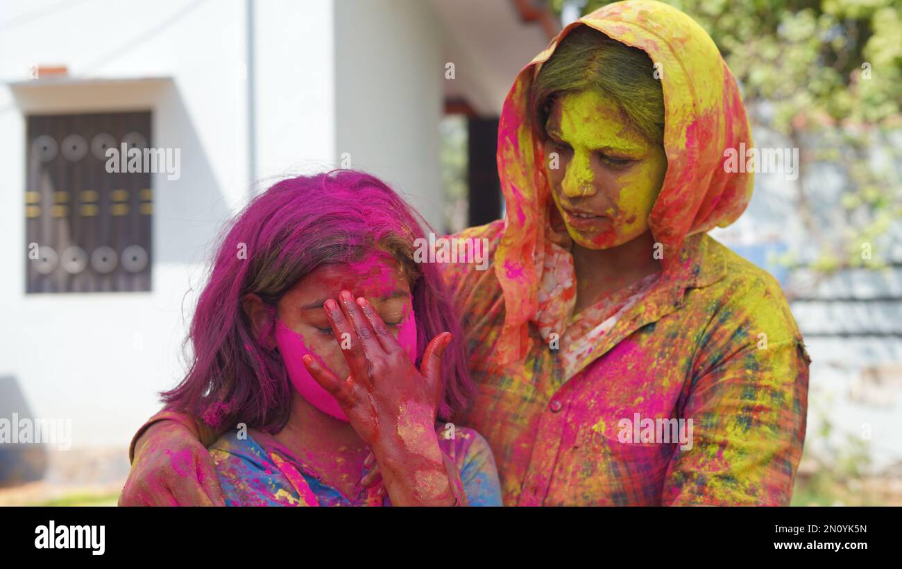 Außenansicht der asiatischen, indischen glücklichen Mutter, Tochter in indischer Kleidung, die das Holi Festival feiert, zusammen mit Farbpulver. Stockfoto