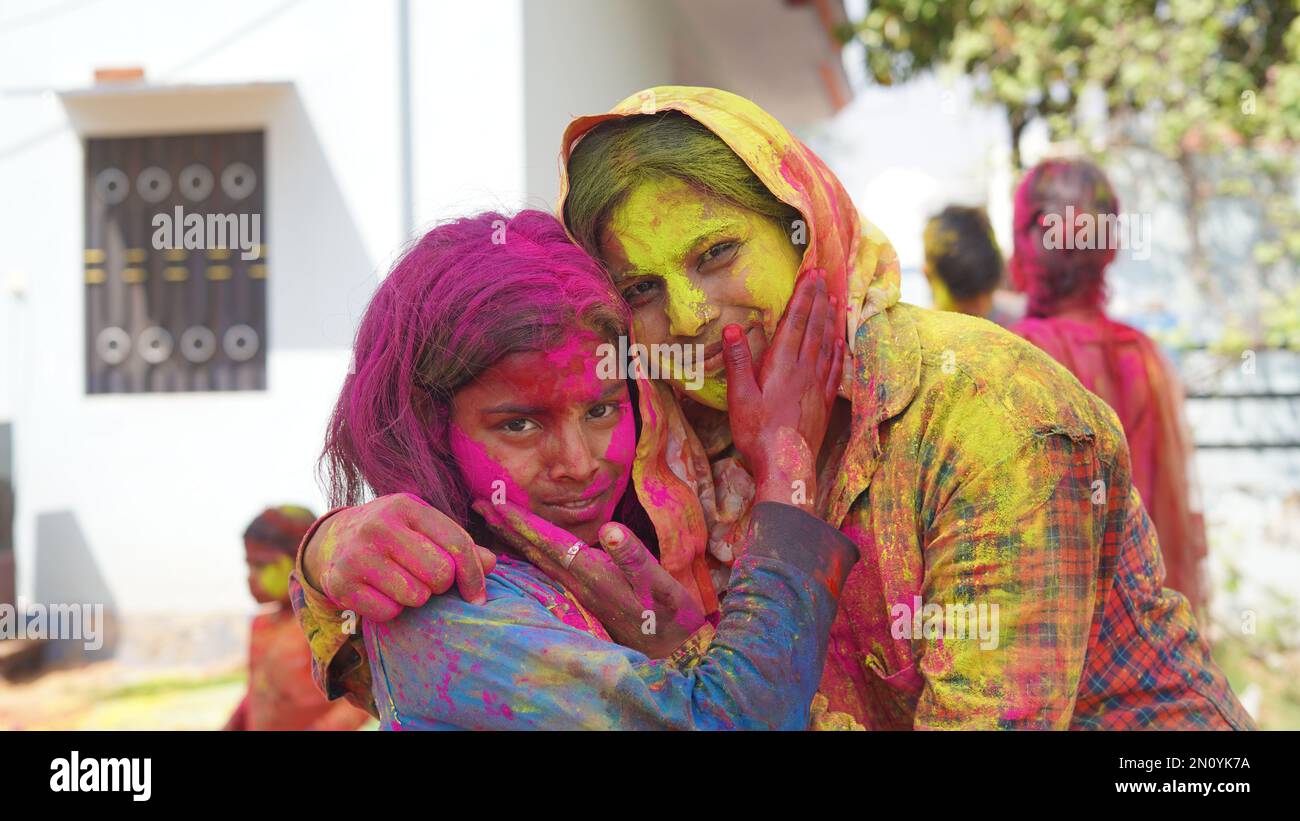 Außenansicht der asiatischen, indischen glücklichen Mutter, Tochter in indischer Kleidung, die das Holi Festival feiert, zusammen mit Farbpulver. Stockfoto