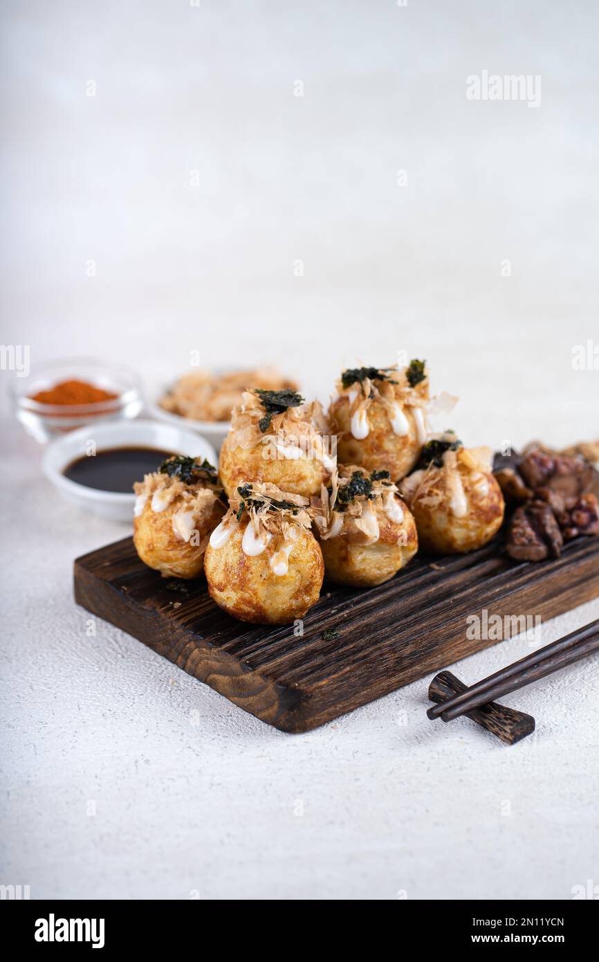 Takoyaki ist ein japanisches Street Food mit Tintenfisch, Wurst oder Käse. Garnieren Sie sie mit Seetang und Katsuobushi Stockfoto