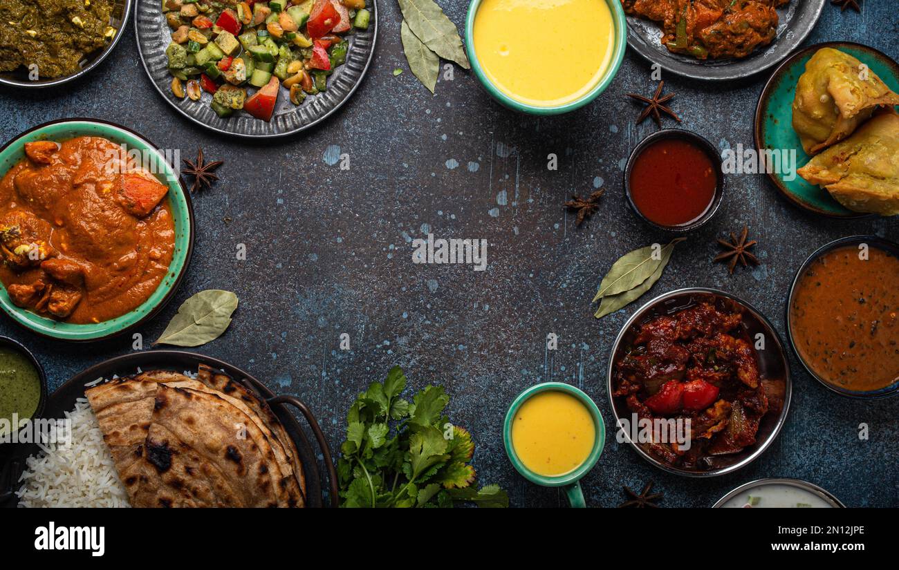 Indisches Ethnic Food Buffet auf Betontisch von oben: Curry, Samosa ...