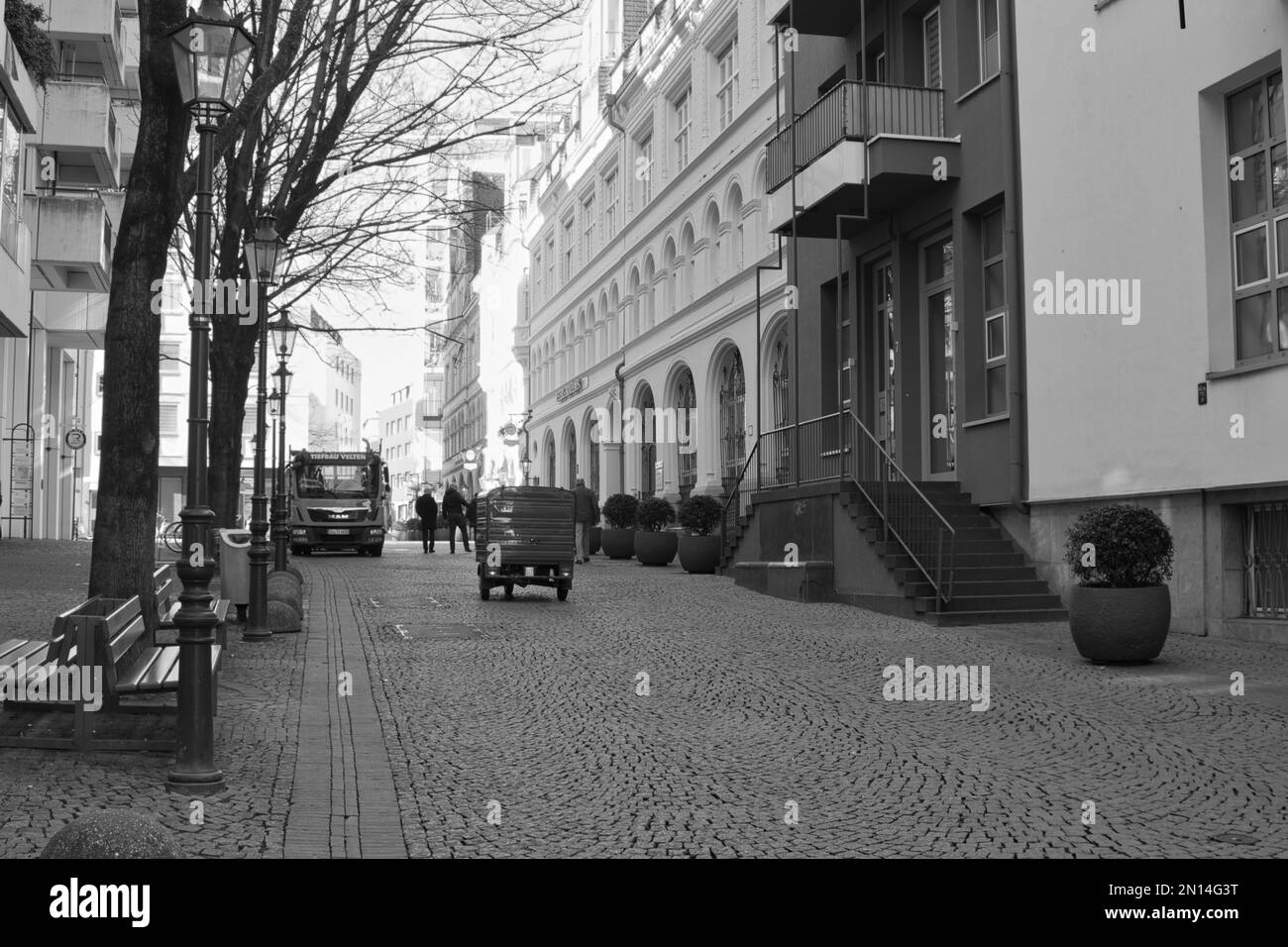 Eine Grauskala-Aufnahme von Gebäuden entlang einer Straße in Köln - Straßenfotografie Stockfoto