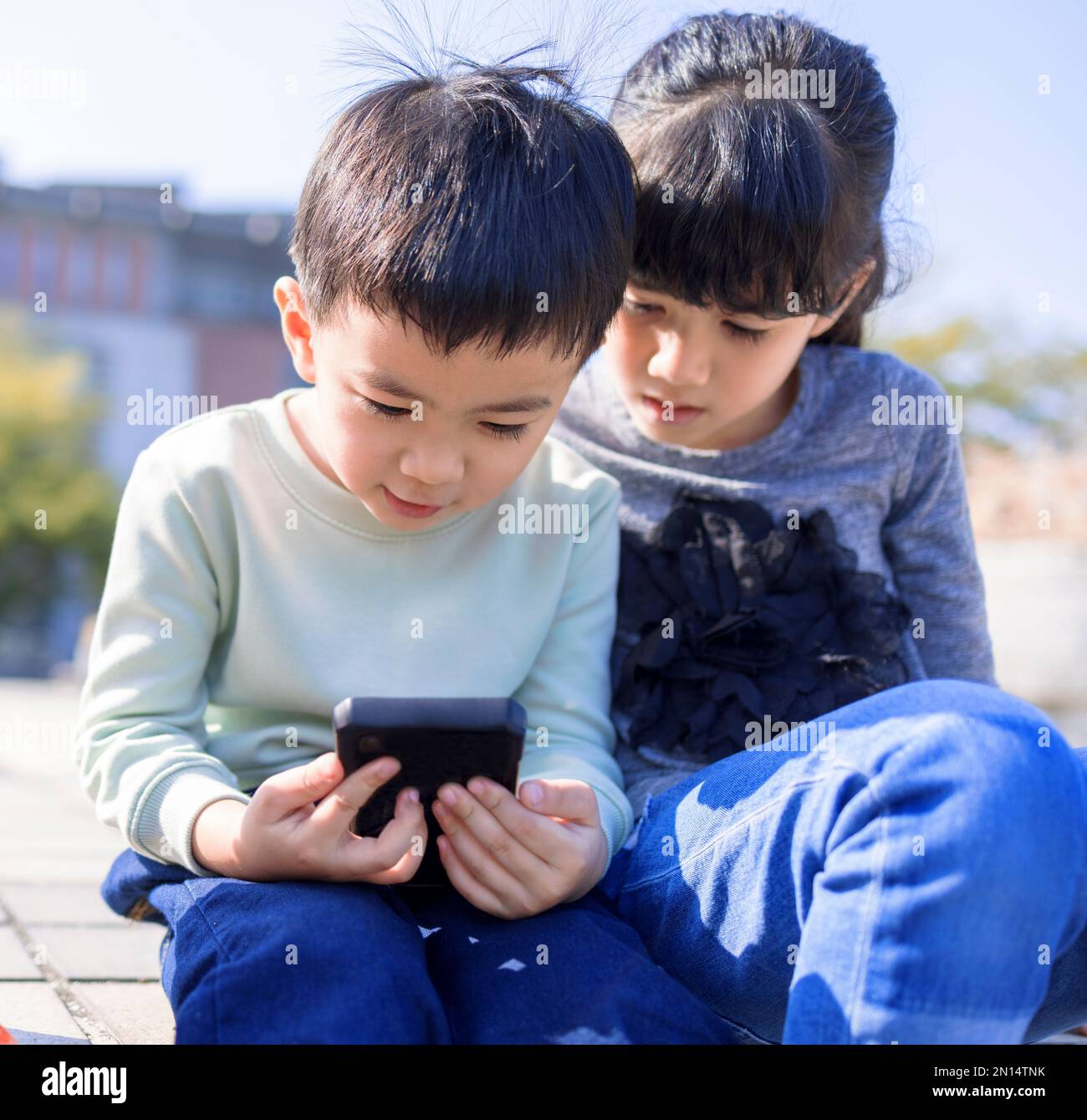 Glückliche Kinder, die in der Schule auf das Handy schauen Stockfoto