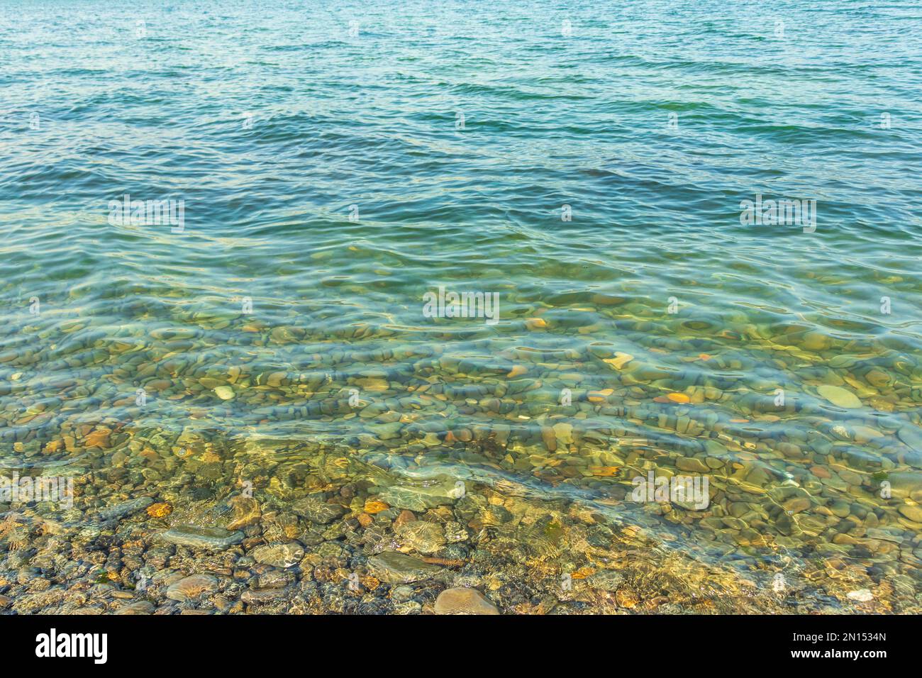 Meeressteine im Meerwasser. Kieselsteine unter Wasser. Die Aussicht von oben. Nautischer Hintergrund. Sauberes Meerwasser. Transparentes Meer. Stockfoto