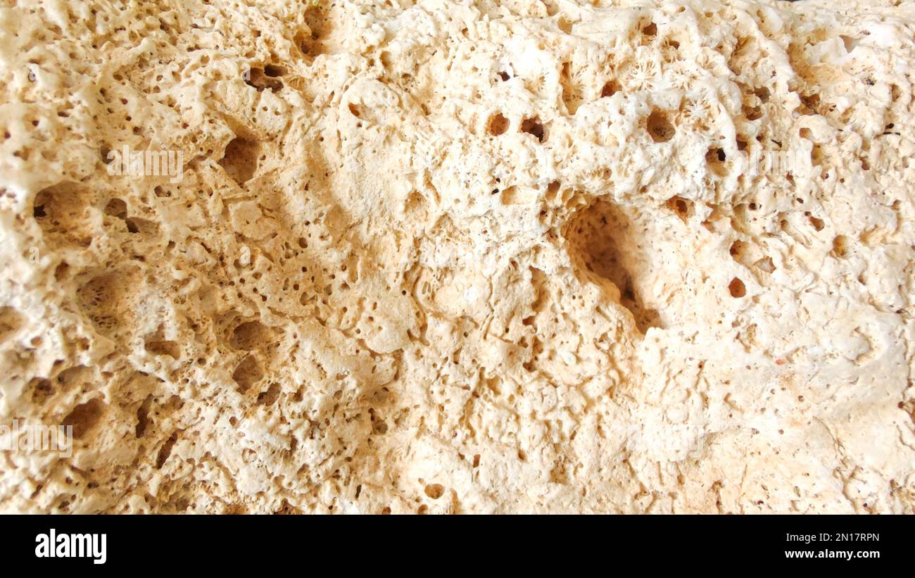 Eine Nahaufnahme der rauen Oberfläche eines Steins, Textur eines gelben Kalksteins Stockfoto