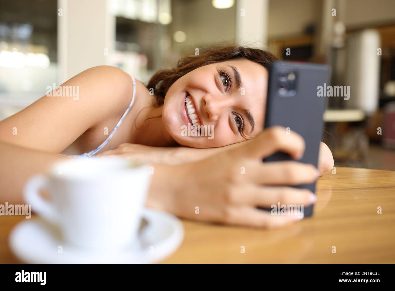 Eine glückliche Frau, die das Telefon in einem Restaurant benutzt Stockfoto