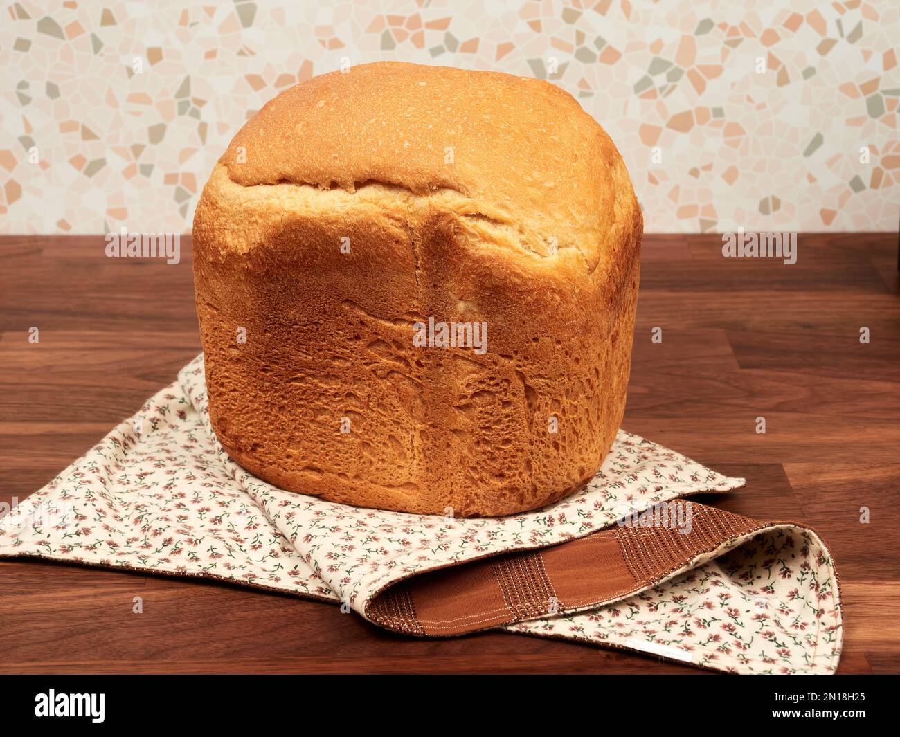 Hausgemachtes Brot mit einer Brotmaschine auf einer Serviette auf einem Walnusstisch Stockfoto