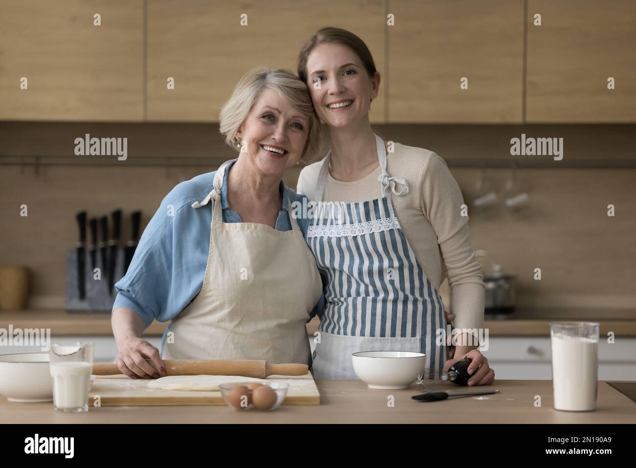 Fröhliche, reife Mutter und Erwachsene Tochter, die am Tisch backen Stockfoto