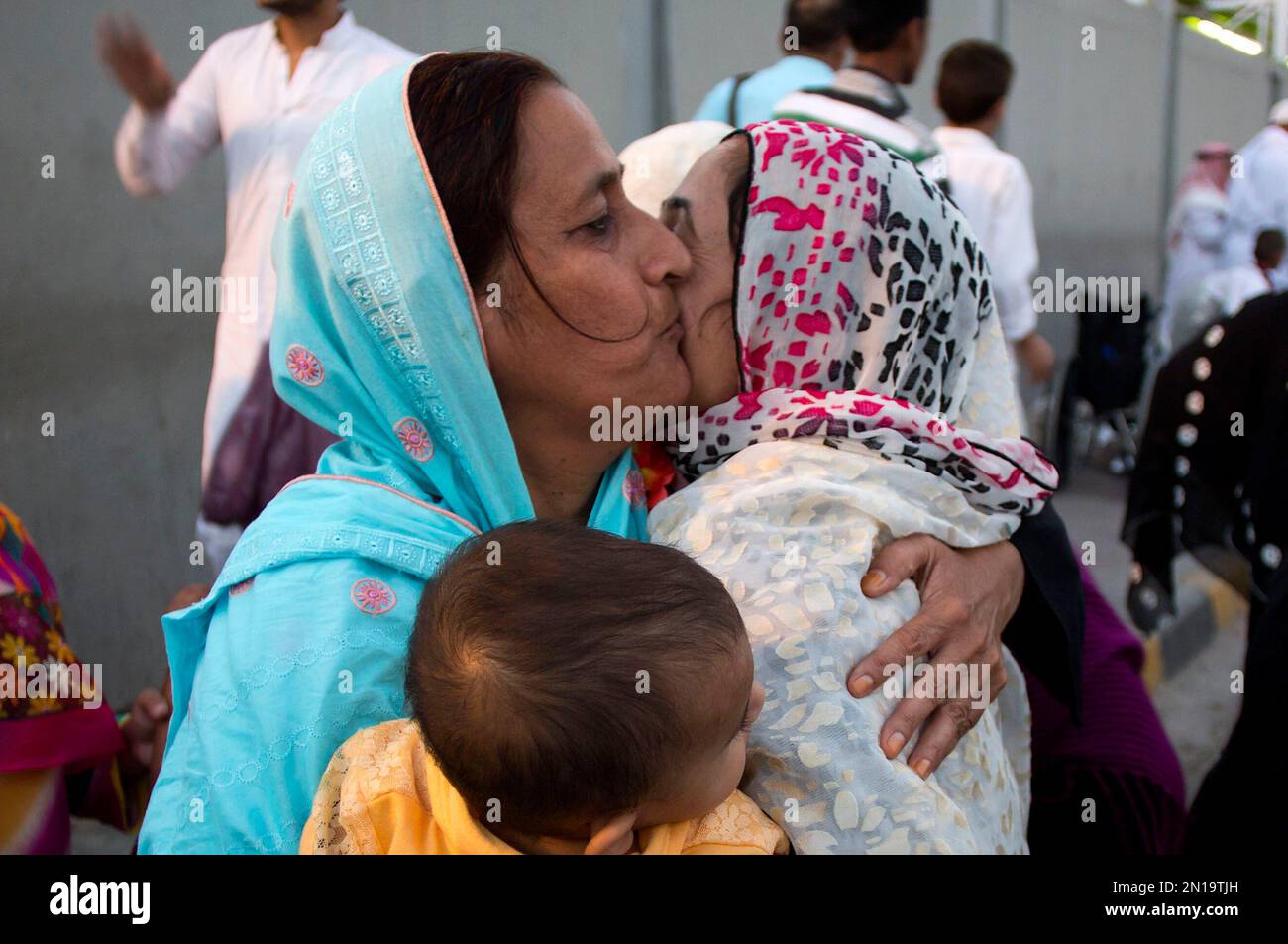 A Pakistani woman greets a family member, left, arrived from Saudi ...