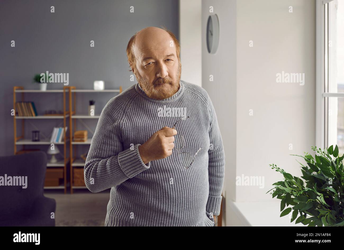 Porträt eines selbstbewussten Seniorenmannes, der eine Brille in der Hand hält Stockfoto