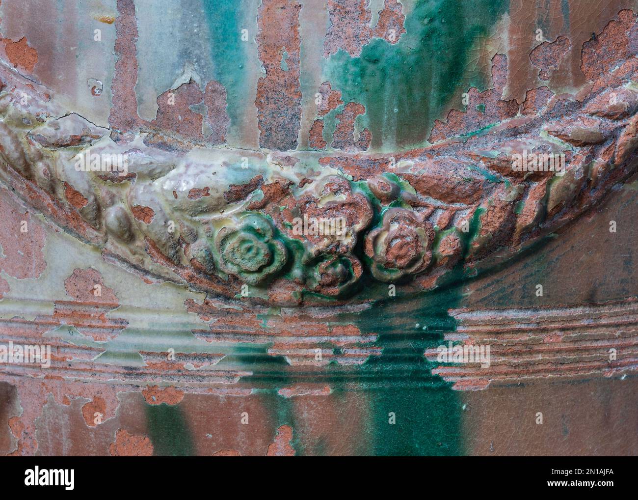 Detailansicht der alten glasierten Keramik aus der Nahaufnahme mit Blumen- und Blattgirlande Stockfoto
