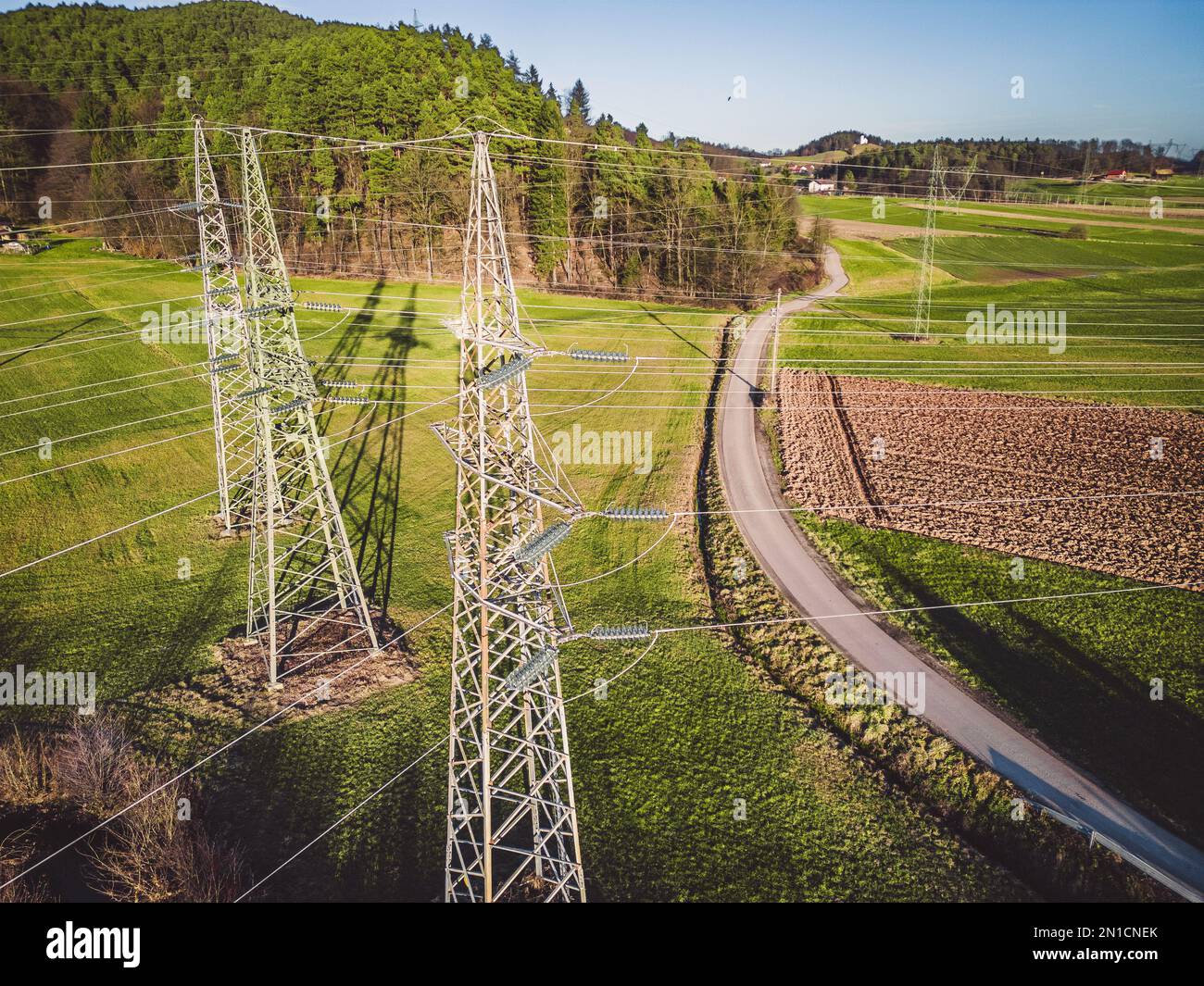 Drohnenansicht von drei Strommasten auf dem Land Stockfoto