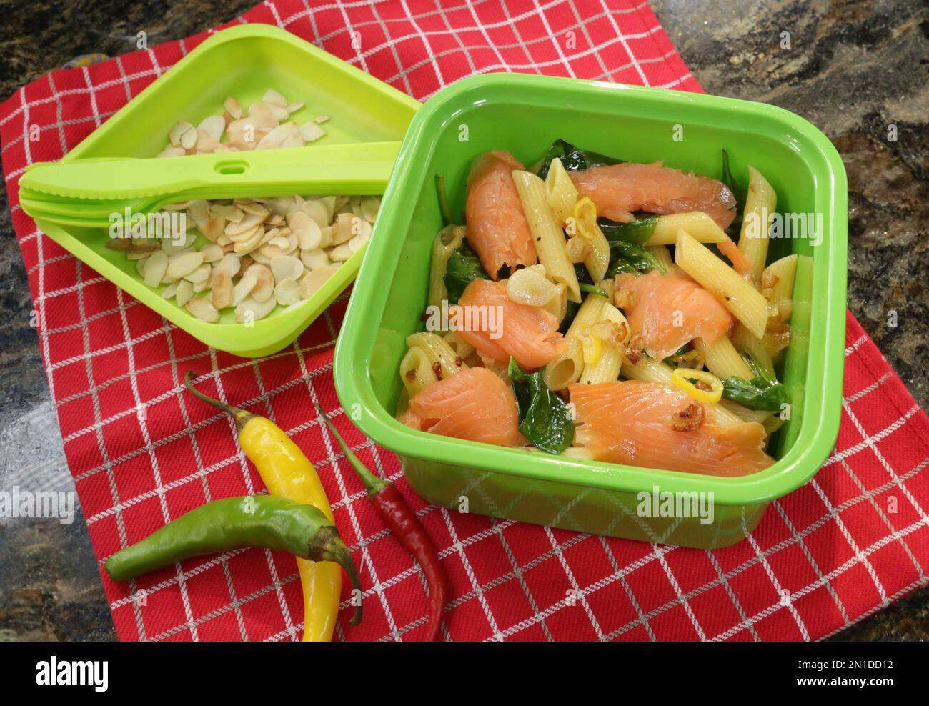Nudelpenne mit geräuchertem Lachs, Spinat, Chilipfeffer und Mandelflocken zum Mitnehmen. Stockfoto