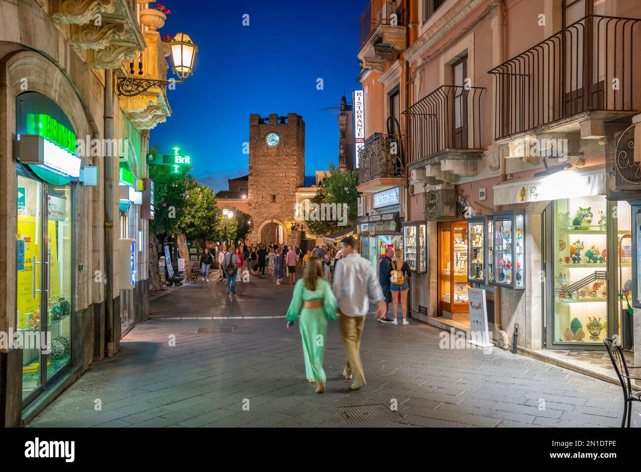 Blick auf den Torre dell'Orologio e Porta di Mezzo und die geschäftige Straße in Taormina in der Abenddämmerung, Taormina, Sizilien, Italien, Mittelmeer, Europa Stockfoto