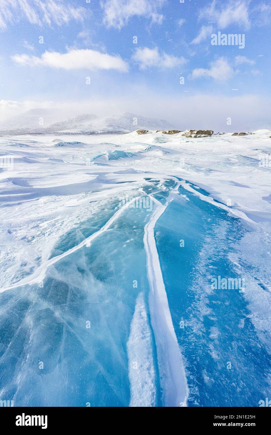 Durchsichtiges Eis mit Wellen, das einen See in einer verschneiten Landschaft bedeckt, Stora Sjofallet, Norrbotten County, Lappland, Schweden, Skandinavien, Europa Stockfoto
