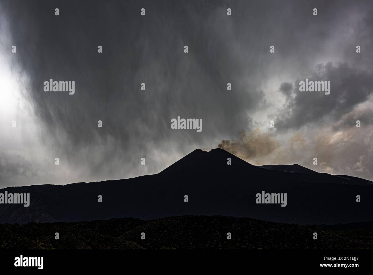 Ein dramatischer Blick auf einen heftigen Regensturm über dem rauchenden Südostkrater des Ätna in Sizilien, Europas höchstem und aktivsten Vulkan Stockfoto