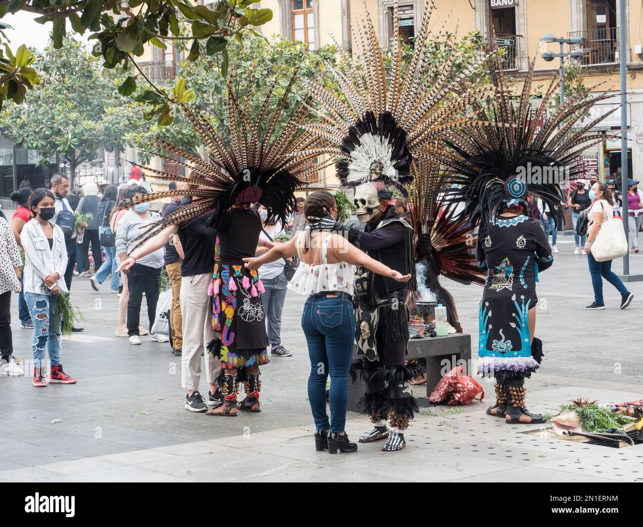 Die Menschen stehen Schlange, um traditionelle Zeremonien von indigenen Priestern in modernen Versionen der aztekischen Zeremonialkleidung, Mexiko-Stadt, Mexiko zu erhalten Stockfoto