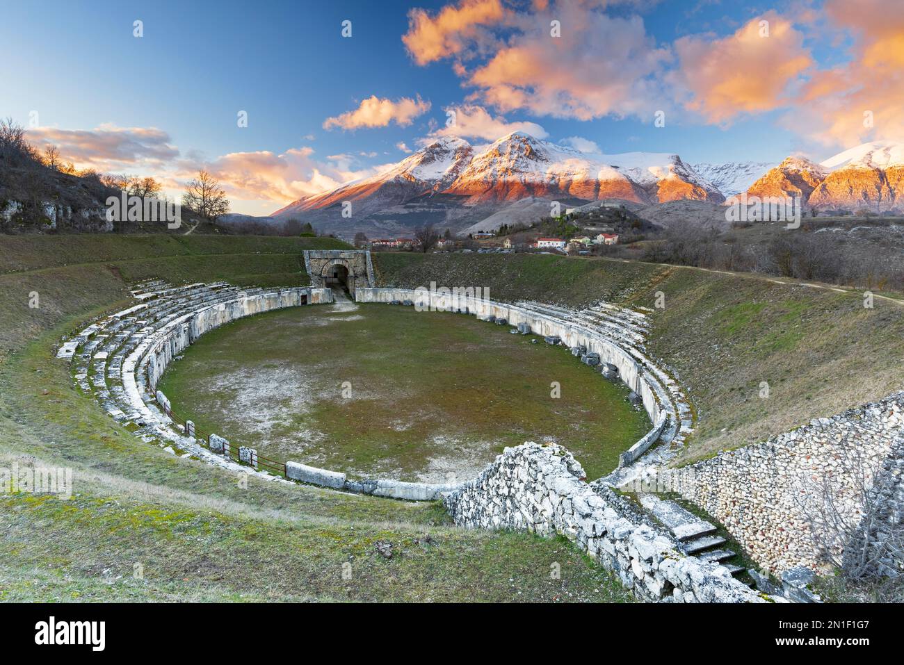 Blick auf das römische Amphitheater und die schneebedeckten Gipfel bei Sonnenuntergang, Alba Fucens, die Provinz L'Aquila, Apenninen, Abruzzen, Italien, Europa Stockfoto