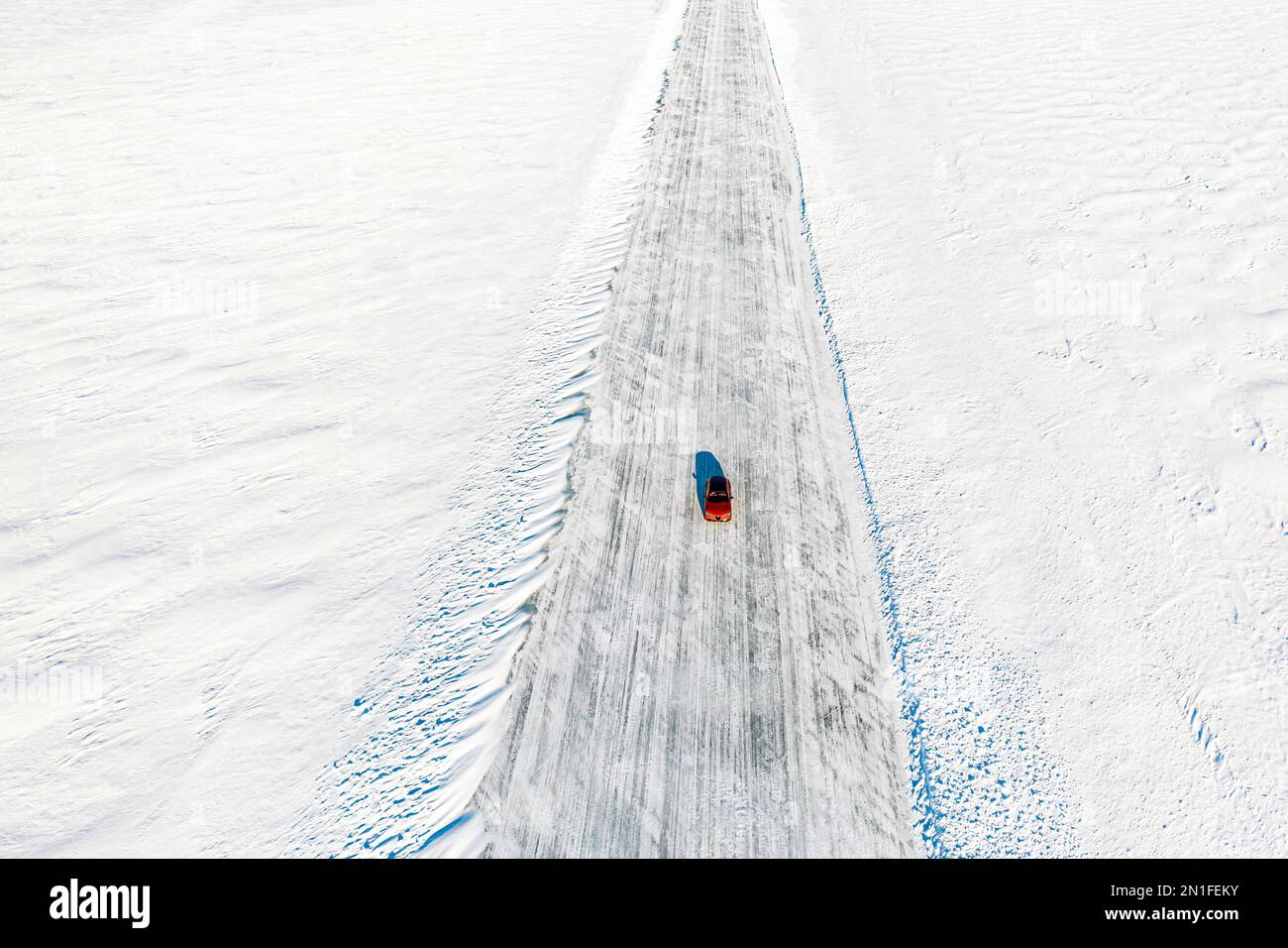 Kalte Wintersonne über einem isolierten Auto, das auf einer Eisstraße auf dem gefrorenen Meer unterwegs ist, Luftaufnahme, Lulea, Norrbotten County, Lappland, Schweden, Skandinavien, Europa Stockfoto