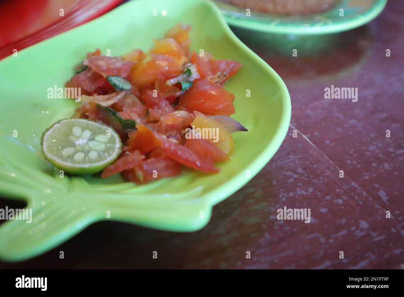Tomate Sambal oder scharfe Tomate Sambal mit Zutaten, Schalotten, roten Chilis, Knoblauch und Salz. Serviert mit gegrilltem Fisch. Stockfoto