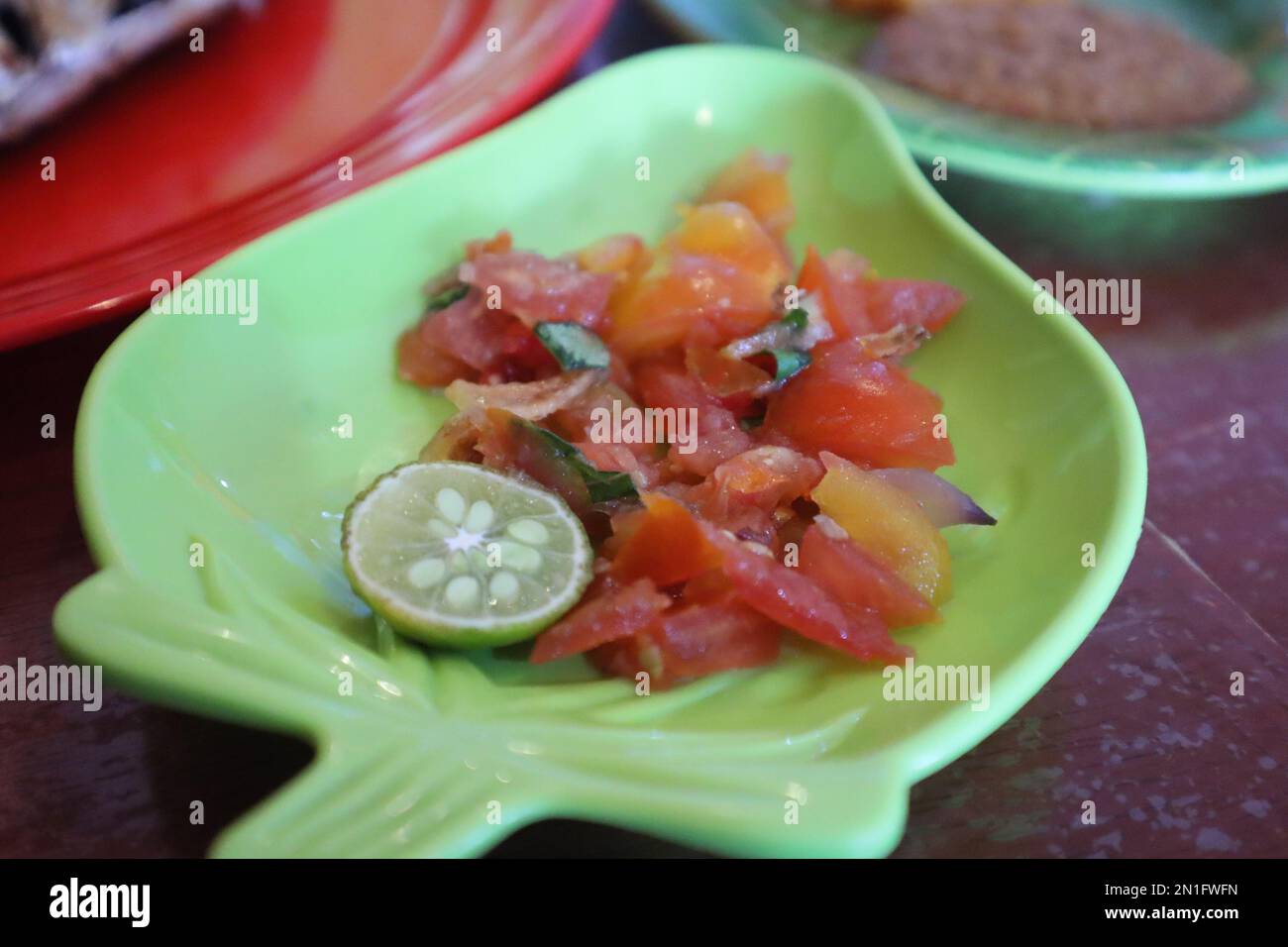 Tomate Sambal oder scharfe Tomate Sambal mit Zutaten, Schalotten, roten Chilis, Knoblauch und Salz. Serviert mit gegrilltem Fisch. Stockfoto